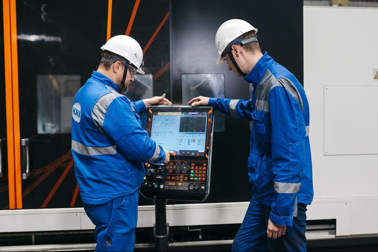 An engineer working beside an automated machine on a production floor